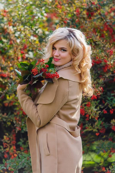 Hermosa mujer elegante de pie junto arbusto de arándano en el parque de otoño — Foto de Stock