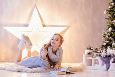 Döşeme ve bir tatil iç Noel ağacı altında kitap okuma güzel genç kadın