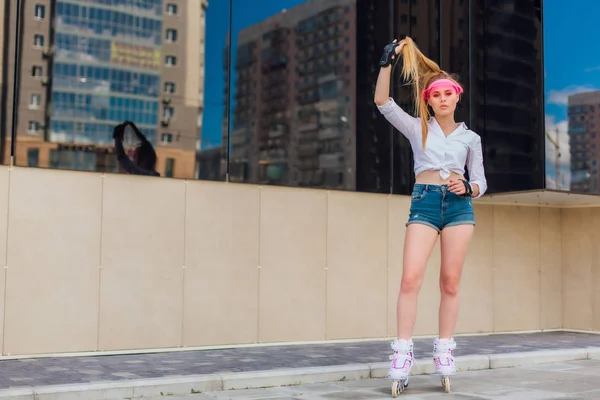 Портрет эмоциональной девушки в розовом колпаке и защитные перчатки для роликов и скейтбординга на роликах по дороге . — стоковое фото