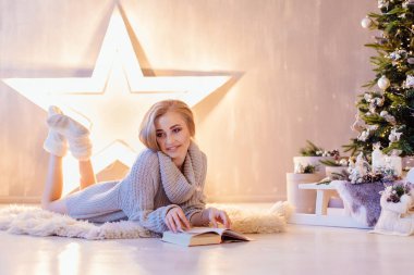 Döşeme ve bir tatil iç Noel ağacı altında kitap okuma güzel genç kadın