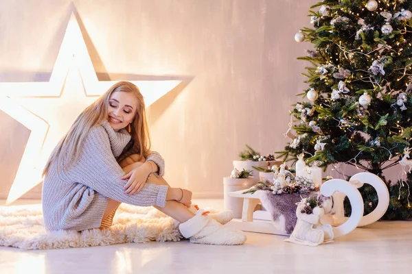 Schöne junge Frau posiert unter dem Weihnachtsbaum in einem Urlaub Interieur — Stockfoto