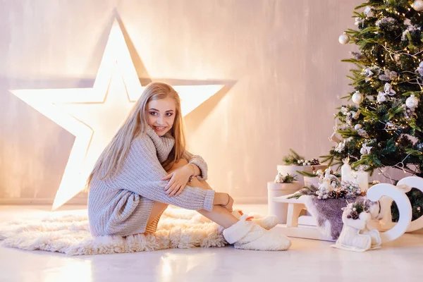 Hermosa joven posando bajo el árbol de Navidad en un interior de vacaciones —  Fotos de Stock