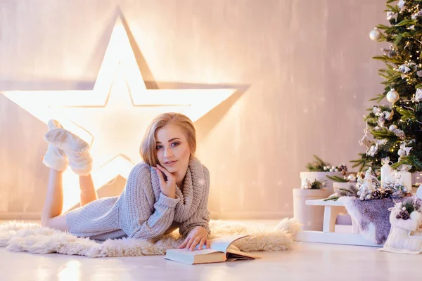 Döşeme ve bir tatil iç Noel ağacı altında kitap okuma güzel genç kadın