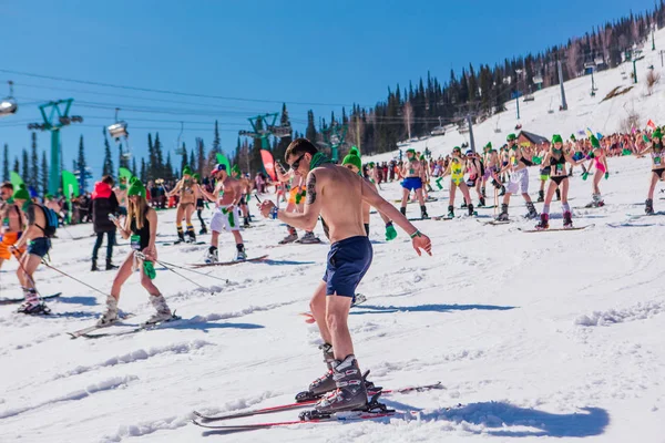 Sheregesh, región de Kemerovo, Rusia - 13 de abril de 2019: multitud de personas en bikini y pantalones cortos montando snowboard y esquí de montaña en la pista — Foto de Stock