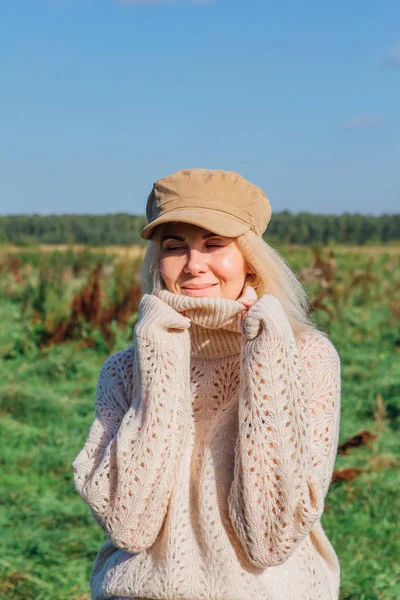 Mujer rubia hermosa feliz caminando en un campo verde — Foto de Stock