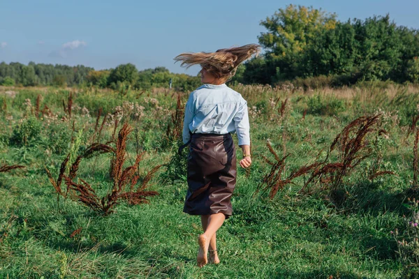 Счастливая молодая красивая женщина ходит по зеленому полю — стоковое фото