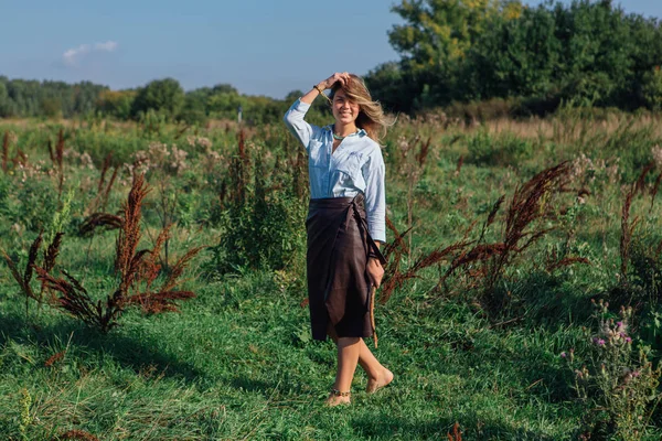 Счастливая молодая красивая женщина ходит по зеленому полю — стоковое фото