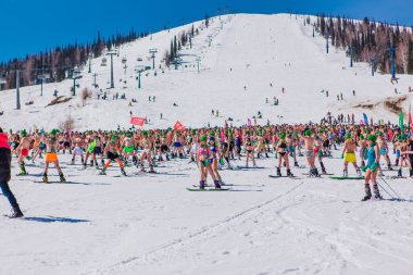 Sheregesh, Kemerovo bölgesi, Rusya - 13 Nisan 2019: Yokuşta snowboard ve dağ kayağı yapan bikinili ve şortlu bir kalabalık