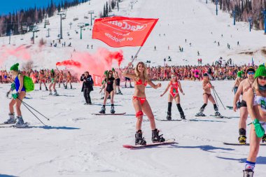 Sheregesh, Kemerovo bölgesi, Rusya - 13 Nisan 2019: Yokuşta snowboard ve dağ kayağı yapan bikinili ve şortlu bir kalabalık