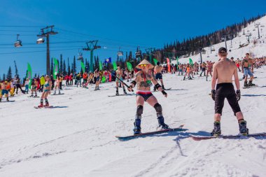 Sheregesh, Kemerovo bölgesi, Rusya - 13 Nisan 2019: Yokuşta snowboard ve dağ kayağı yapan bikinili ve şortlu bir kalabalık
