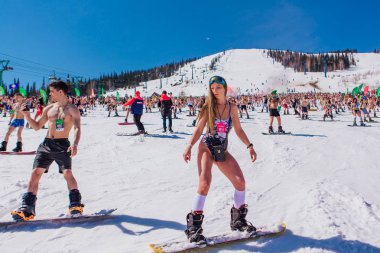 Sheregesh, Kemerovo bölgesi, Rusya - 13 Nisan 2019: Yokuşta snowboard ve dağ kayağı yapan bikinili ve şortlu bir kalabalık