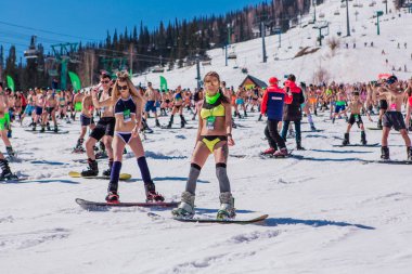 Sheregesh, Kemerovo bölgesi, Rusya - 13 Nisan 2019: Yokuşta snowboard ve dağ kayağı yapan bikinili ve şortlu bir kalabalık