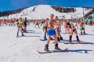 Sheregesh, Kemerovo bölgesi, Rusya - 13 Nisan 2019: Yokuşta snowboard ve dağ kayağı yapan bikinili ve şortlu bir kalabalık