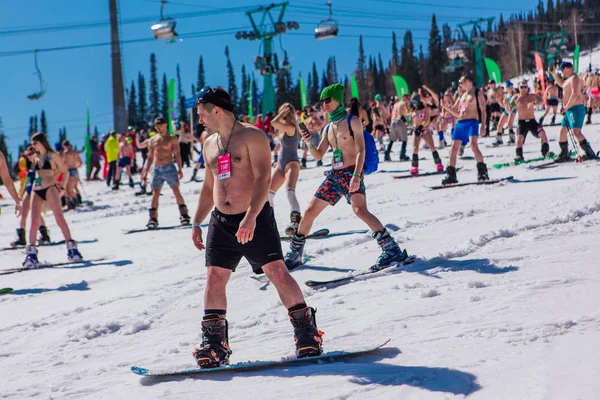 Sheregesh, Kemerovo region, Russia - April 13, 2019 : Crowd of people in bikini and shorts riding snowboard and mountain ski on the slope — 스톡 사진
