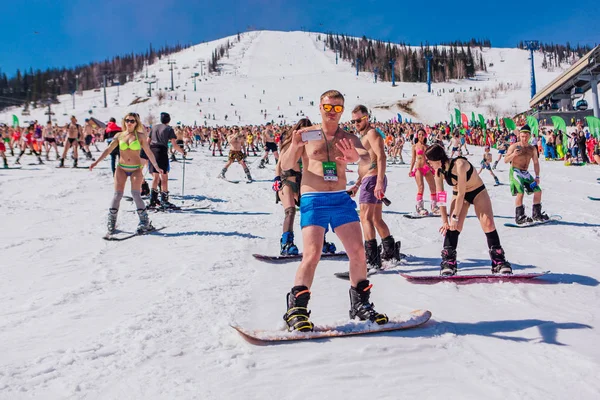 Sheregesh, regio Kemerovo, Rusland - 13 april 2019: Een menigte mensen in bikini en shorts die snowboarden en bergskiën op de piste — Stockfoto