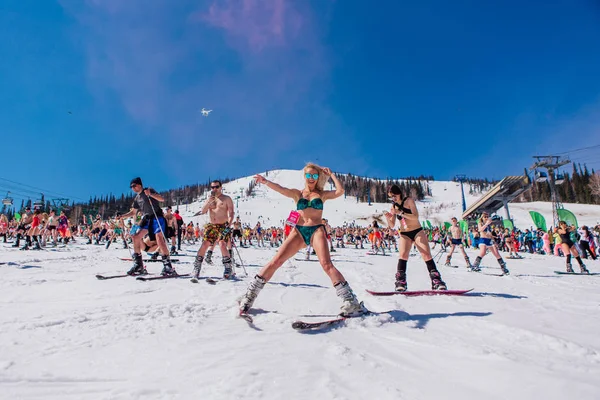 Sheregesh, regio Kemerovo, Rusland - 13 april 2019: Een menigte mensen in bikini en shorts die snowboarden en bergskiën op de piste — Stockfoto