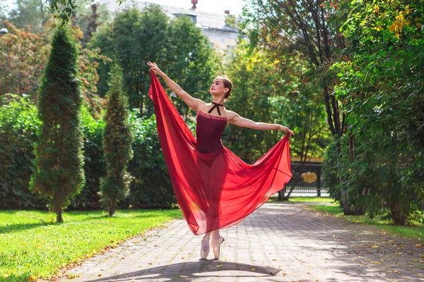 Bailarina de mujer en vestido de ballet rojo bailando en zapatos puntiagudos en el parque de otoño . —  Fotos de Stock