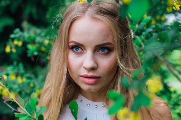 Retrato de cerca de una encantadora mujer rubia con hermoso vestido blanco de pie junto al arbusto de arándanos . —  Fotos de Stock