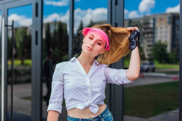 Potret seorang gadis emosional dengan topi merah muda dan sarung tangan pelindung untuk rollerblades dan skateboard . — Stok Foto