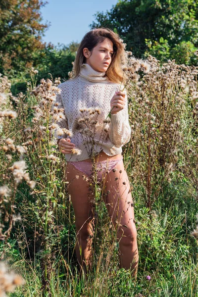 Feliz joven hermosa mujer en suéter y calzoncillos caminando con pie desnudo en un campo de agrimonia seca — Foto de Stock