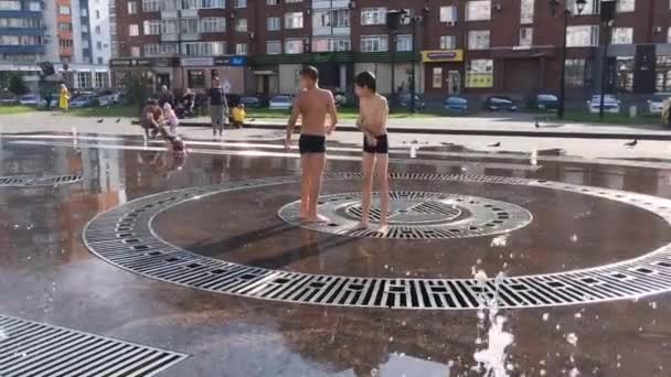 러시아의 노보쿠즈네츠크 - 2018 년 8 월 29 일: 행복 한 십 대 청소년들 이 도시의 샘에서 물을 튀기고 더운 날 시원 한 물줄기를 즐긴다. — 비디오