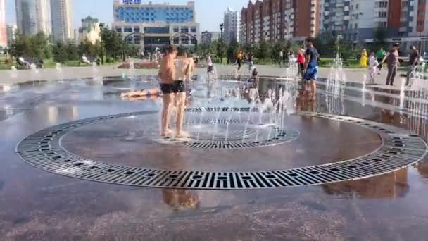 Novokuznetsk, regio Kemerovo, Rusland - 29 augustus 2019: Gelukkige tieners spetteren in het water van een stadsfontein en genieten van de koele waterstromen op een warme dag. — Stockvideo