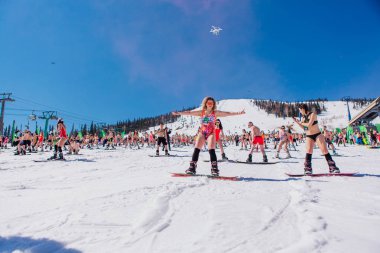 Sheregesh, Kemerovo bölgesi, Rusya - 13 Nisan 2019: Yokuşta snowboard ve dağ kayağı yapan bikinili ve şortlu bir kalabalık