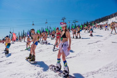Sheregesh, Kemerovo bölgesi, Rusya - 13 Nisan 2019: Yokuşta snowboard ve dağ kayağı yapan bikinili ve şortlu bir kalabalık