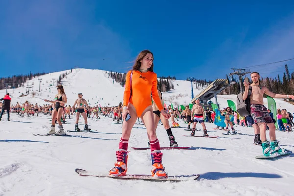 Sheregesh, región de Kemerovo, Rusia - 13 de abril de 2019: multitud de personas en bikini y pantalones cortos montando snowboard y esquí de montaña en la pista — Foto de Stock
