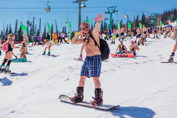 Sheregesh, kemerowo region, russland - 13. April 2019: Mann in kurzen Hosen auf Snowboard und hallo five auf der Piste — Stockfoto