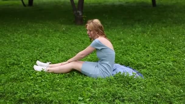 Mladá krásná dospívající dívka ležící na trávě v parku v zamračeném dni, usmívající se, relaxační koncept, koncept snění — Stock video