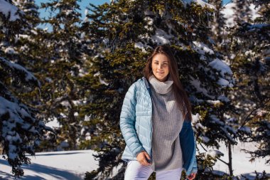 Kışın karlı dağ manzarasında mavi gözlü ve yüzünde çiller olan güzel esmer bir kadının portresi. Kışın açık havada güzel bir kız.