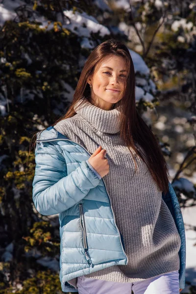 Potret seorang wanita muda berambut cokelat indah dengan mata biru dan bintik-bintik di wajah di musim dingin bersalju pegunungan lanskap. Gadis cantik di musim dingin di luar ruangan . — Stok Foto