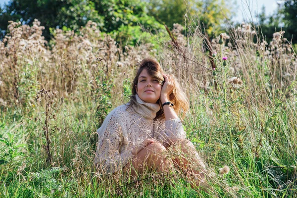 스웨터를 입고 속옷 차림의 행복 한 젊은 여성 이 맨발로 마른 부조화 밭에 앉아 있는 모습 — 스톡 사진