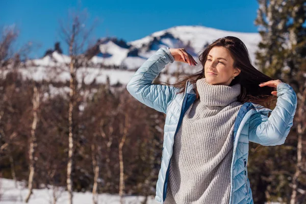 Retrato de una joven hermosa morena con ojos azules y pecas en la cara en invierno nevado paisaje de montaña. Hermosa chica en el invierno al aire libre . — Foto de Stock