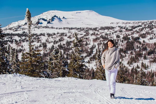 Kışın karlı dağ manzarasında mavi gözlü ve yüzünde çiller olan güzel esmer bir kadının portresi. Kışın açık havada güzel bir kız.