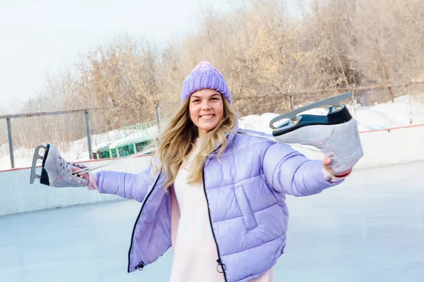 Belle jeune femme avec des patins à glace suspendus sur le cou sur la patinoire . — Photo