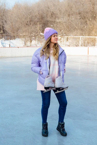 Adorável jovem com patins de gelo pendurado no pescoço na pista de gelo . — Fotografia de Stock