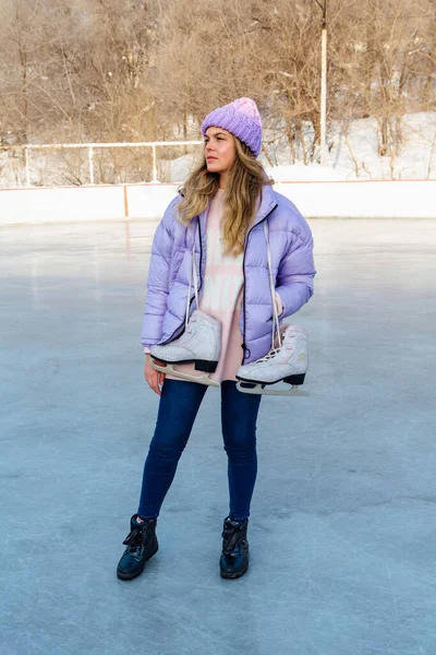 Preciosa joven con patines de hielo colgando del cuello en la pista de hielo . —  Fotos de Stock