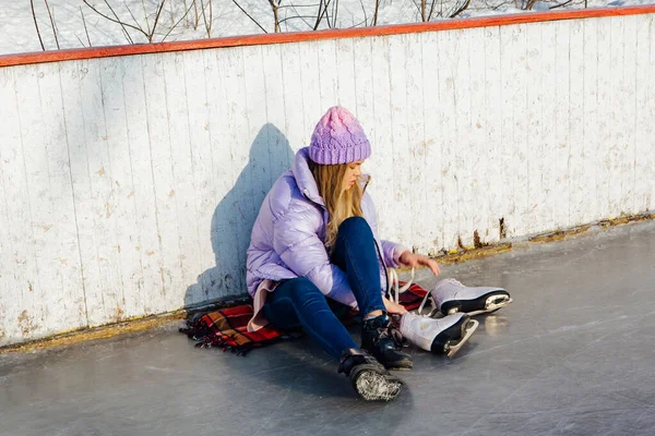 Belle jeune femme assise sur un anneau de glace et attachant lacets — Photo
