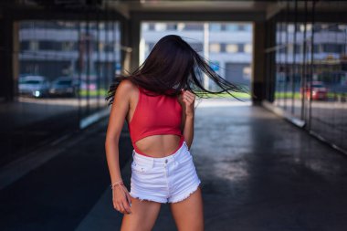 Genç esmer kadın dans ediyor ve saçlarını bina kemerinde sallıyor..