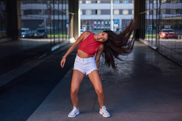 Jeune femme brune dansant et secouant ses cheveux dans l'arche du bâtiment . — Photo