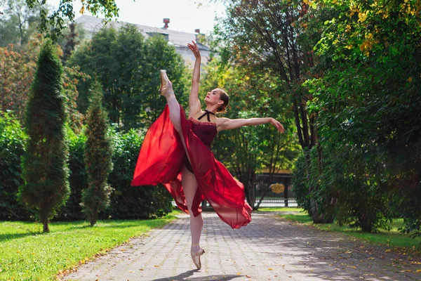 Ballerina donna in abito da balletto rosso che balla in scarpe da punta nel parco autunnale . — Foto Stock