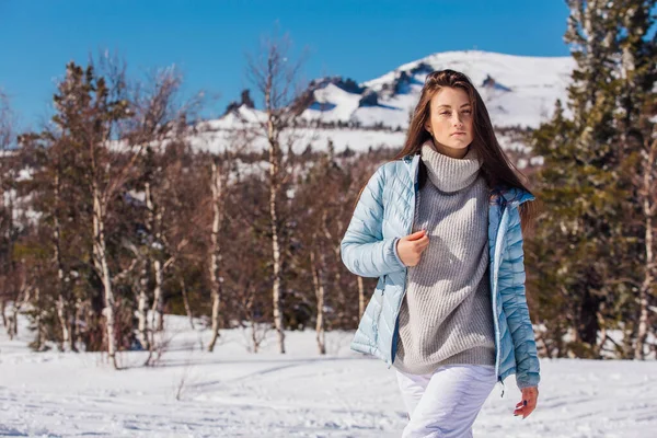 Portrét mladé krásné brunetky s modrýma očima a pihami na tváři v zimě zasněžené horské krajiny. Krásná dívka v zimě venku. — Stock fotografie