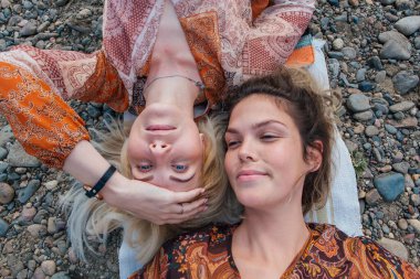 İki güzel genç kadın esmer ve sarışın kafa kafaya yatıyorlar..