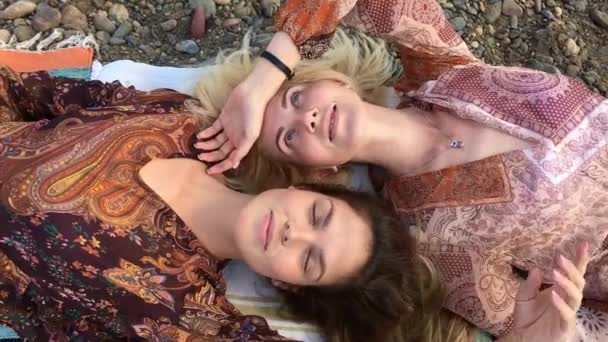 Zwei schöne junge Frauen brünett und blond, die Kopf an Kopf liegen. — Stockvideo