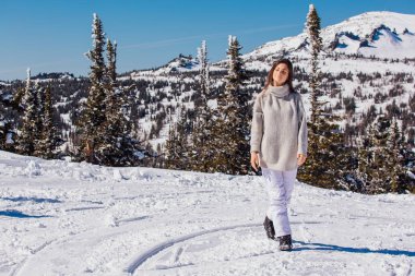 Kışın karlı dağ manzarasında mavi gözlü ve yüzünde çiller olan güzel esmer bir kadının portresi. Kışın açık havada güzel bir kız.