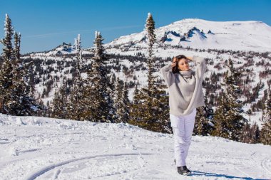 Kışın karlı dağ manzarasında mavi gözlü ve yüzünde çiller olan güzel esmer bir kadının portresi. Kışın açık havada güzel bir kız.