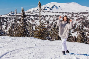 Kışın karlı dağ manzarasında mavi gözlü ve yüzünde çiller olan güzel esmer bir kadının portresi. Kışın açık havada güzel bir kız.