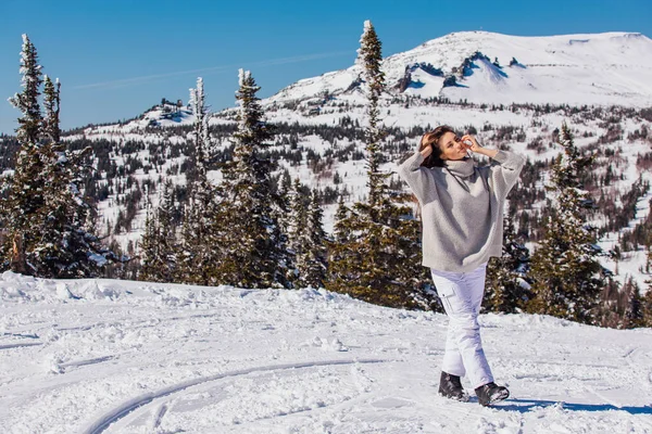 Retrato de una joven hermosa morena con ojos azules y pecas en la cara en invierno nevado paisaje de montaña. Hermosa chica en el invierno al aire libre . — Foto de Stock